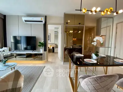 Modern living room with stylish decor and open dining area, featuring sleek furniture and elegant lighting.