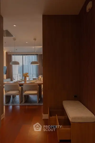 Elegant modern living room with wooden accents and dining area, featuring stylish lighting and city view.