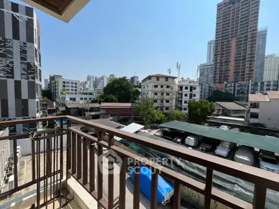 Urban balcony view with cityscape and residential buildings under clear blue sky.