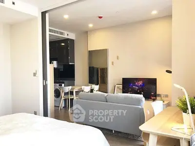 Modern open-plan living room with cozy sofa, TV, and dining area in stylish apartment.