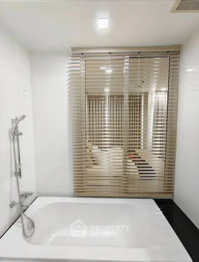 Modern bathroom with sleek bathtub and stylish blinds for privacy.