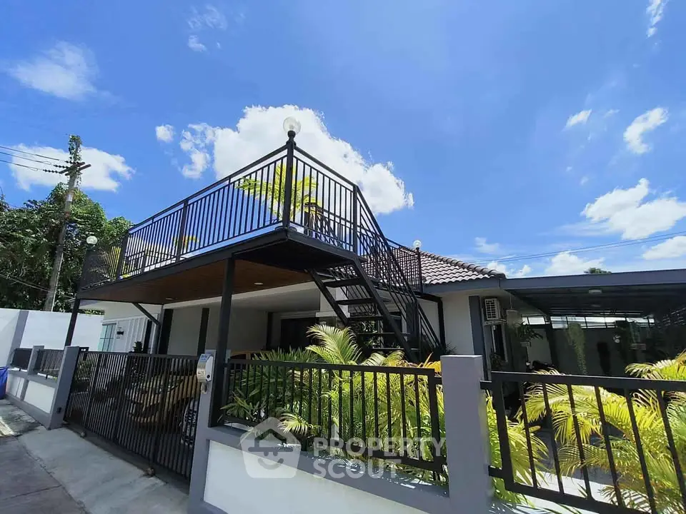 Modern house with rooftop terrace and lush garden under clear blue sky.