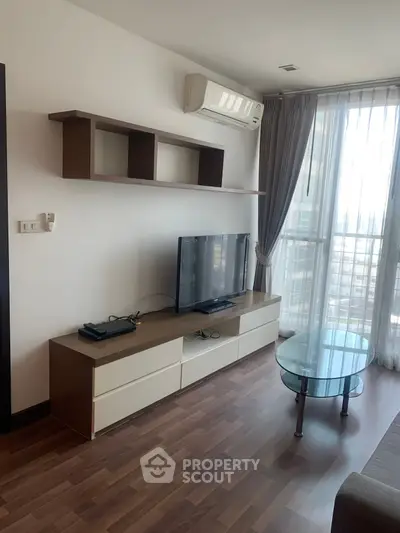 Modern living room with sleek TV unit and large window offering natural light.