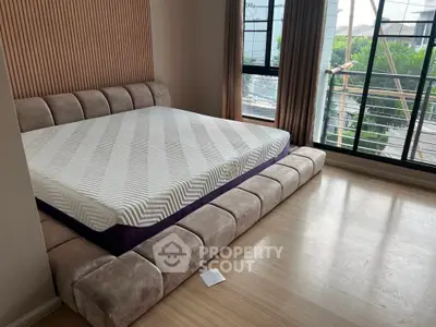 Spacious bedroom with modern bed and large window offering natural light and garden view.