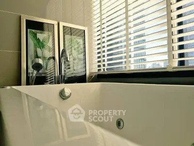 Luxurious bathroom with modern bathtub and city view through blinds.