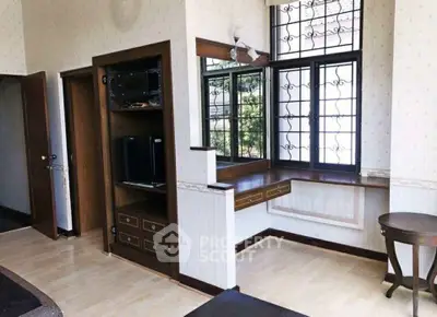 Charming living room with built-in wooden shelves and large windows.