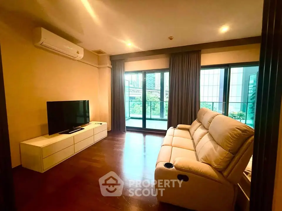 Spacious living room with modern furniture and large windows offering a garden view.