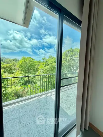 Spacious balcony with lush green view through sliding glass doors