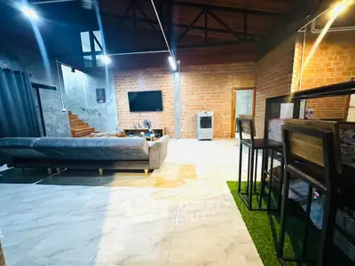 Spacious living room with modern decor and exposed brick walls, featuring a cozy seating area and stylish lighting.