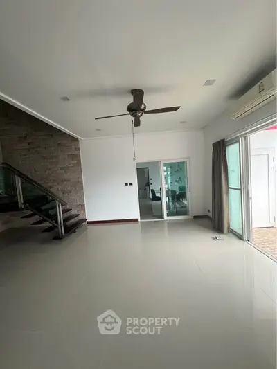 Spacious modern living room with ceiling fan and glass doors leading to patio.
