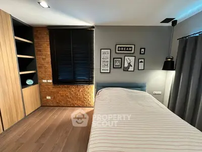 Modern bedroom with stylish decor and wooden flooring, featuring a cozy bed and wall art.