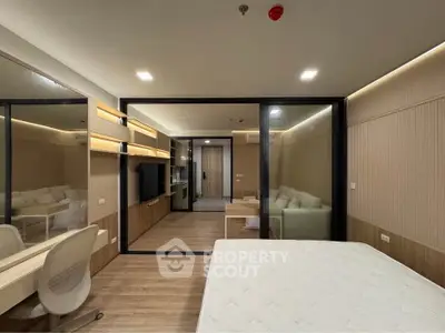 Modern bedroom with sleek design, featuring a glass partition, wooden flooring, and ambient lighting.