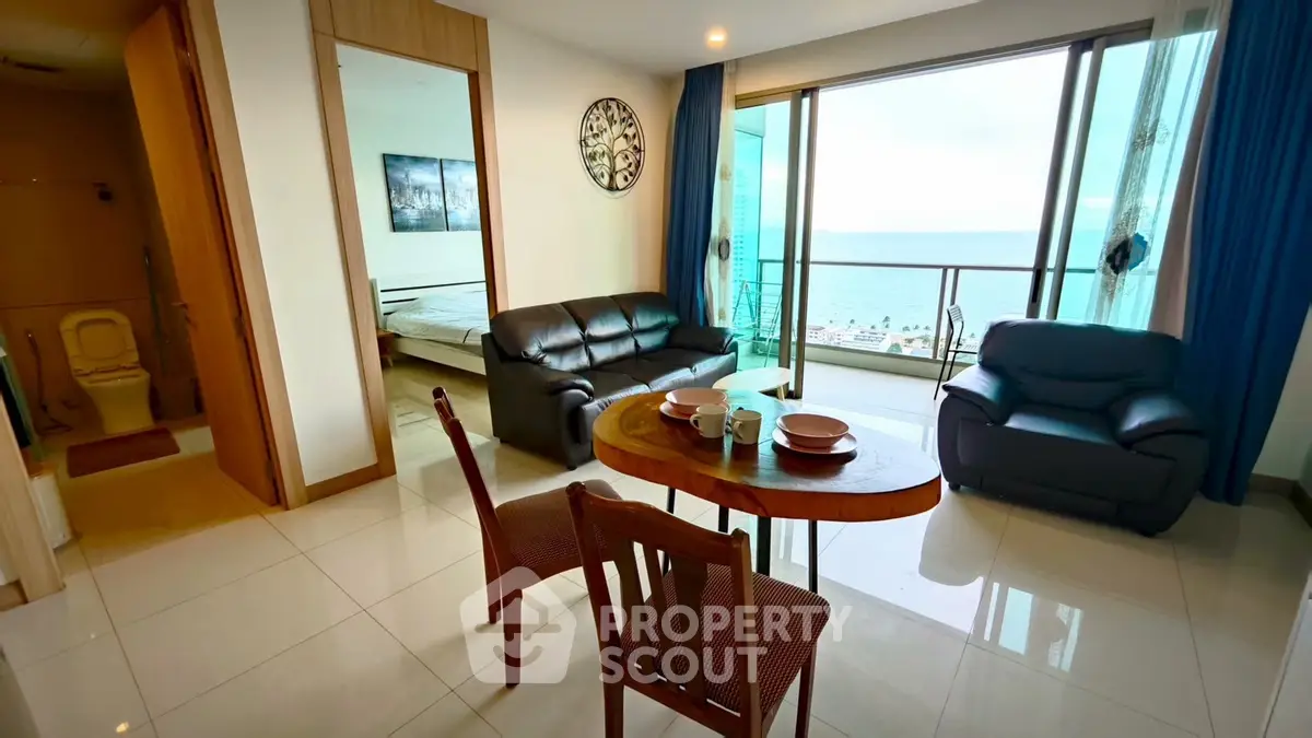 Modern living room with ocean view, featuring sleek furniture and large windows for natural light.