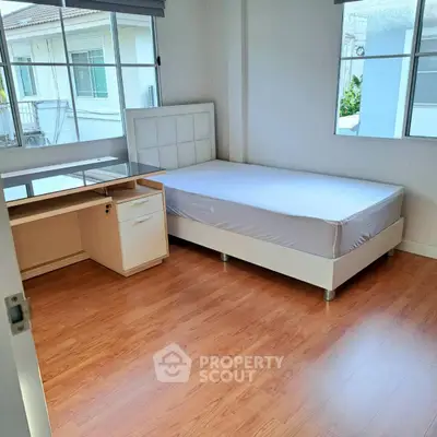 Bright bedroom with wooden flooring, large windows, and a modern bed frame.