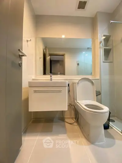 Modern bathroom with sleek fixtures and glass shower enclosure in a contemporary apartment.