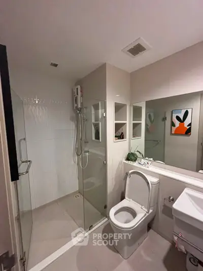 Modern bathroom with glass shower and sleek fixtures in contemporary apartment.