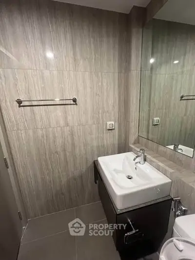 Modern bathroom with sleek sink and large mirror in contemporary design.