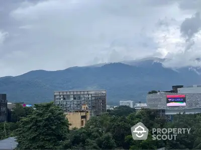 Scenic cityscape with lush greenery and mountain backdrop, featuring modern buildings.