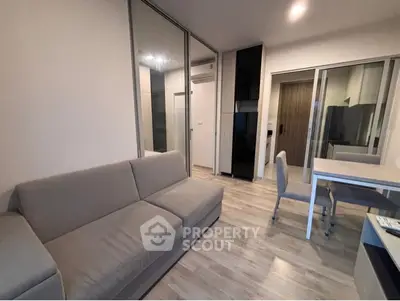 Modern living room with sleek furniture and open layout, featuring a cozy sofa and dining area.