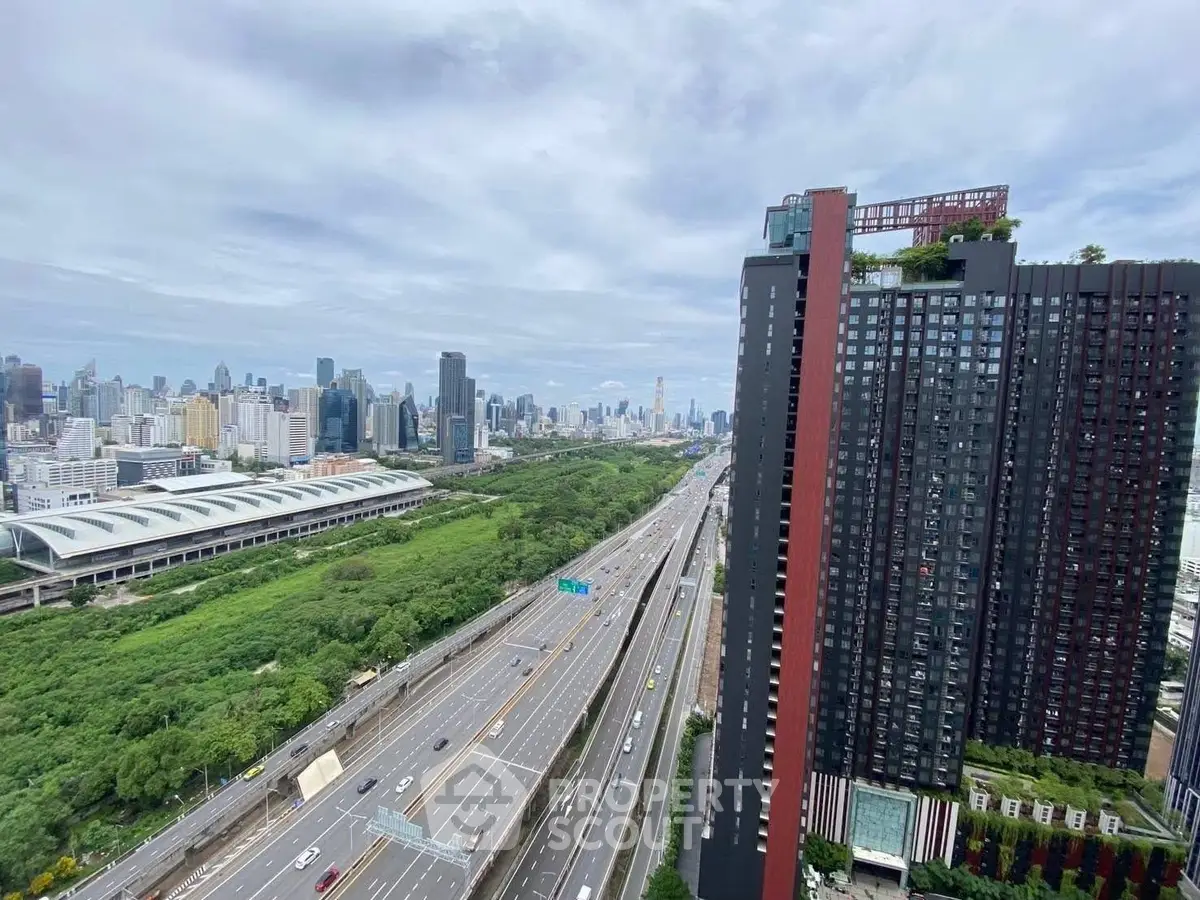 Stunning cityscape view from high-rise building with lush greenery and highway below.