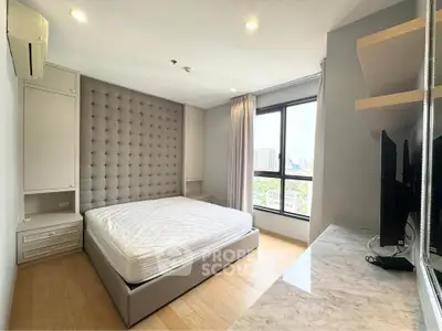 Modern bedroom with large window and city view, featuring a stylish bed and built-in storage.