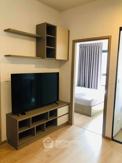 Modern living room with sleek TV unit and view into cozy bedroom