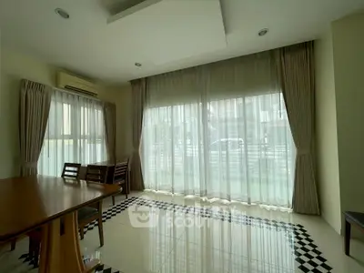 Spacious dining area with large windows and elegant curtains, perfect for natural light and modern living.