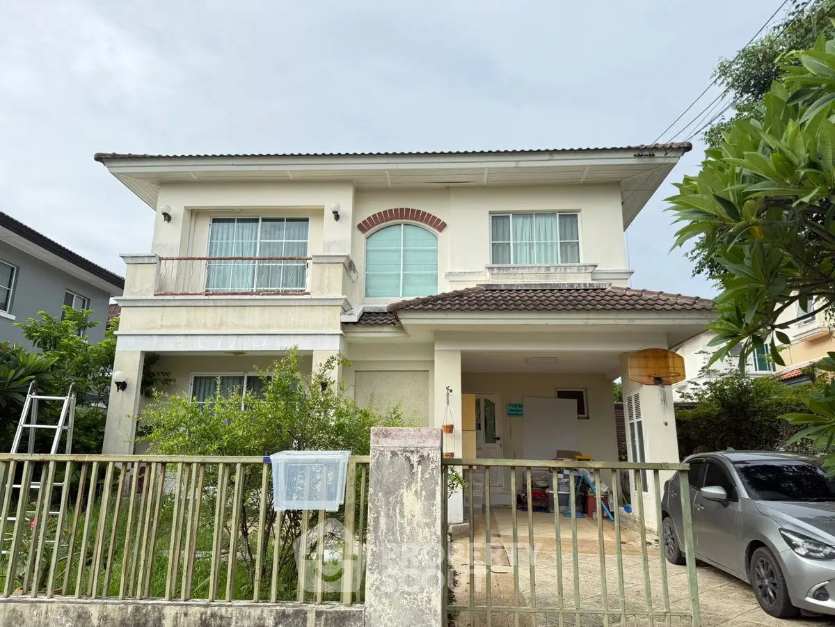 Charming two-story house with a spacious driveway and lush greenery, perfect for family living.