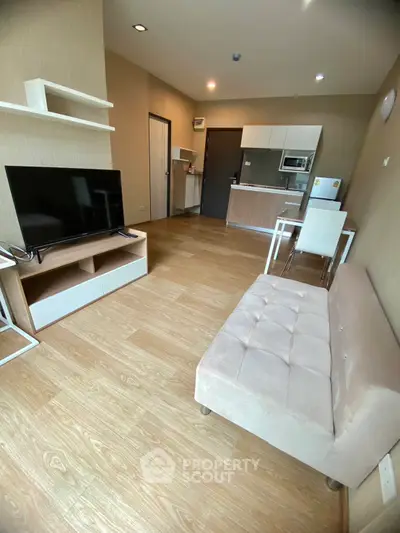 Modern living room with open kitchen, sleek furniture, and wooden flooring