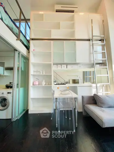 Modern loft apartment with high ceilings, built-in storage, and sleek furniture, featuring a washing machine and air conditioning.
