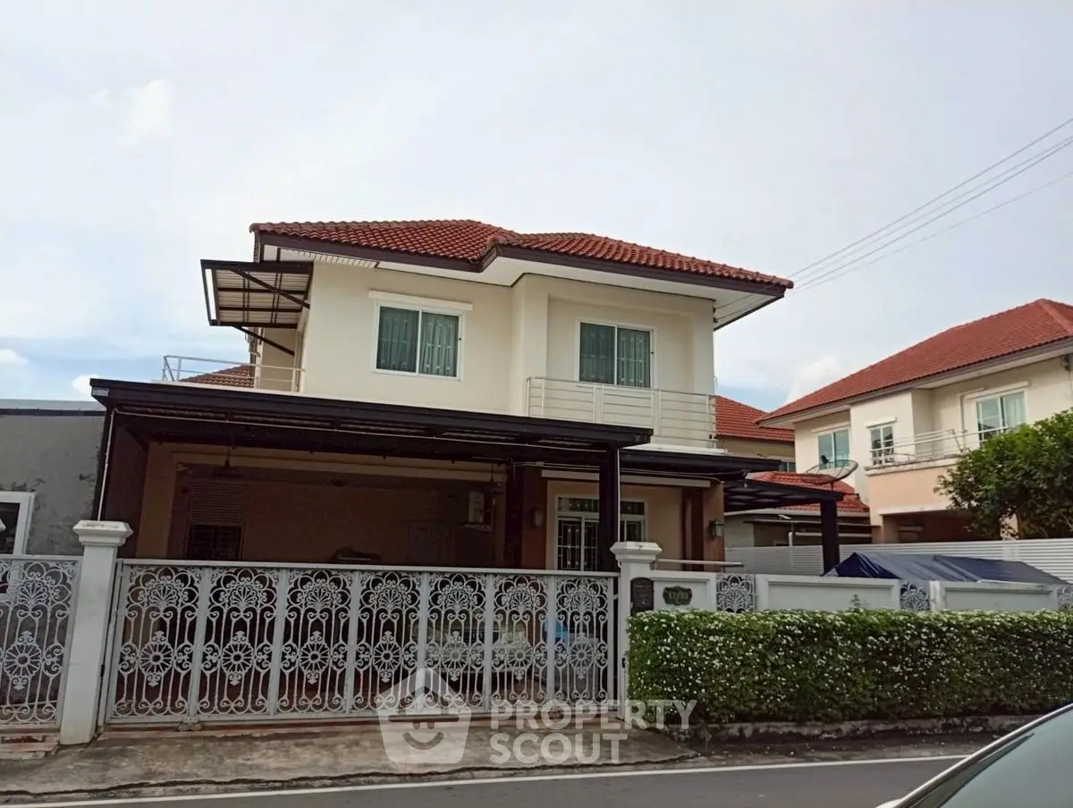 Charming two-story house with red roof and decorative fence in a serene neighborhood.