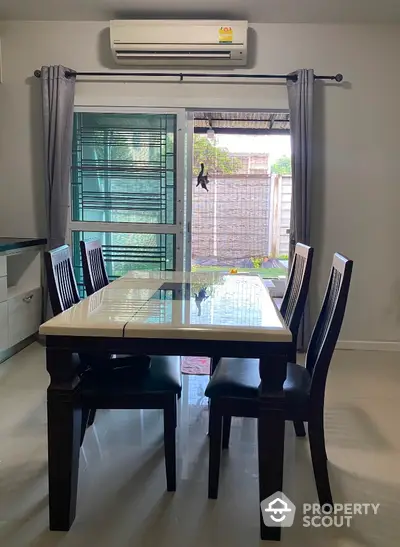 Modern dining area with elegant table and chairs, featuring large window with garden view.