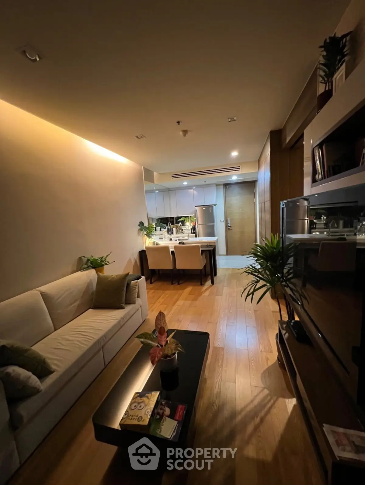 Modern living room with cozy seating and elegant dining area, featuring warm lighting and stylish decor.