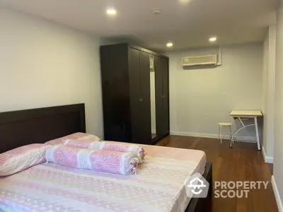 Spacious bedroom with wooden flooring and modern furniture in a cozy apartment.