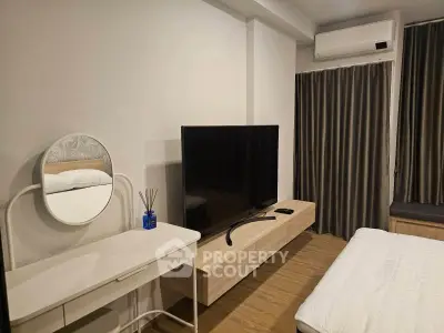 Modern bedroom with sleek TV setup and stylish vanity in a cozy apartment.