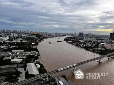 Stunning river view from high-rise building with city skyline and train bridge.