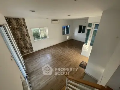 Spacious empty living room with wooden flooring and large windows for natural light.