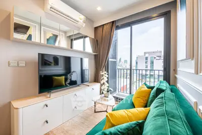 Modern living room with green sofa, large TV, and city view balcony.