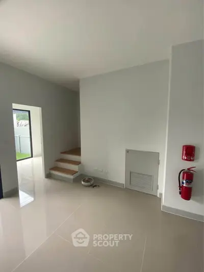 Modern minimalist interior with sleek staircase and glossy tile flooring, featuring a fire extinguisher for safety.
