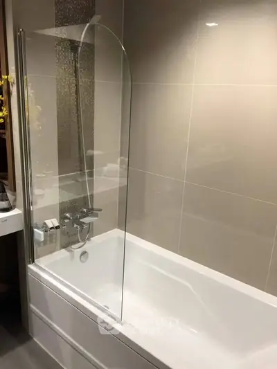 Modern bathroom with sleek bathtub and glass shower screen in contemporary design.