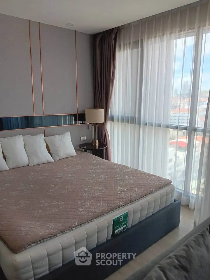 Luxurious bedroom with large windows offering stunning city views, elegant decor, and cozy ambiance.