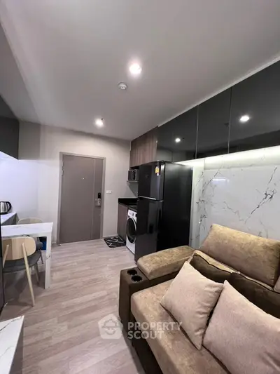 Modern living room with sleek kitchen, cozy sofa, and stylish decor in a contemporary apartment.