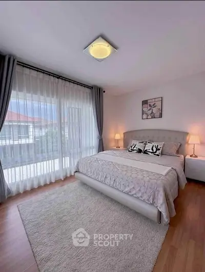 Spacious bedroom with large windows and elegant decor, perfect for relaxation.