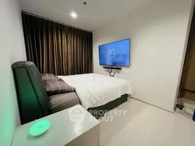 Modern bedroom with sleek design, featuring a wall-mounted TV and cozy bedding.