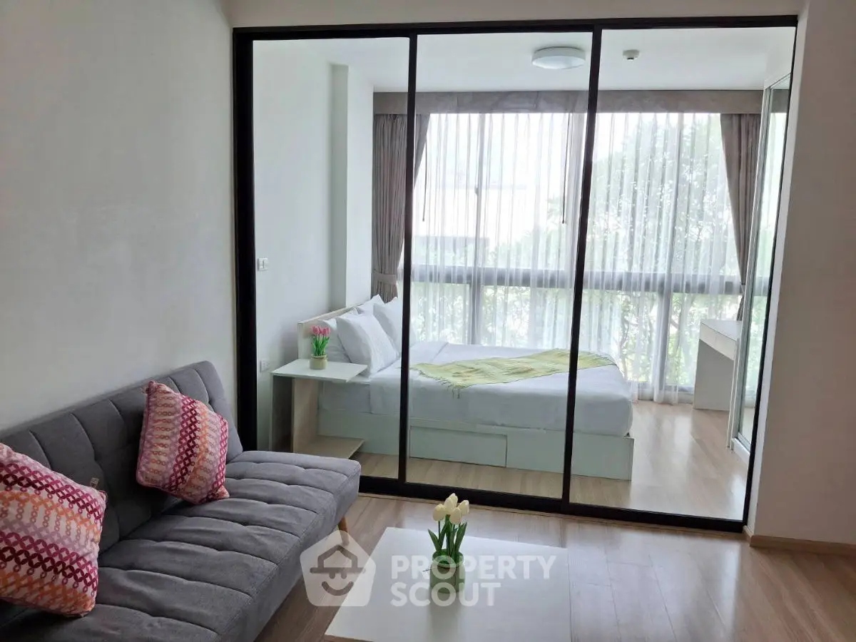 Modern studio apartment with glass partition, cozy living area, and bright bedroom.