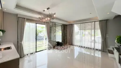 Spacious modern living room with elegant chandelier and large windows for natural light.