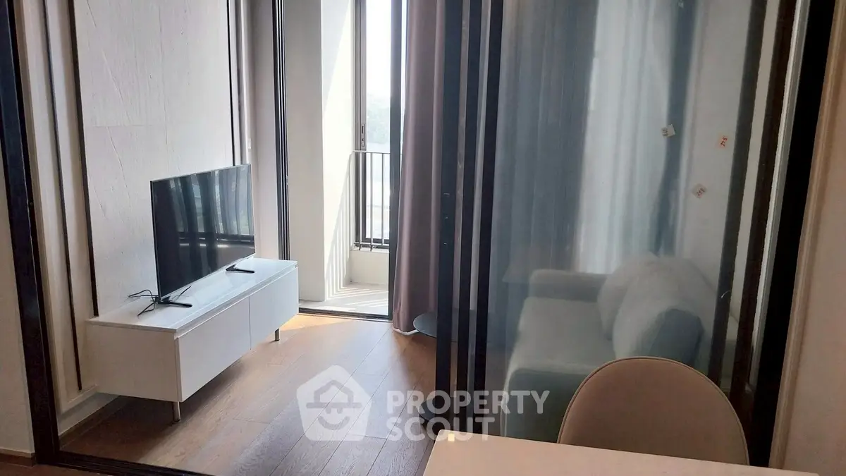 Modern living room with sleek TV unit and cozy seating area near balcony.
