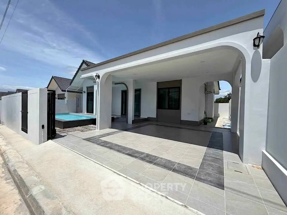 Modern single-story home with spacious driveway and pool, featuring sleek architecture and outdoor living space.