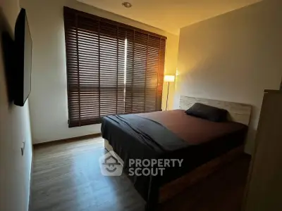 Cozy bedroom with wooden flooring and modern blinds, perfect for relaxation.