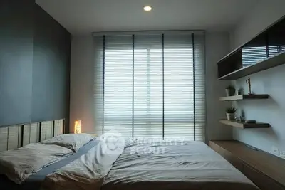 Modern bedroom with sleek design and natural light through large window blinds.